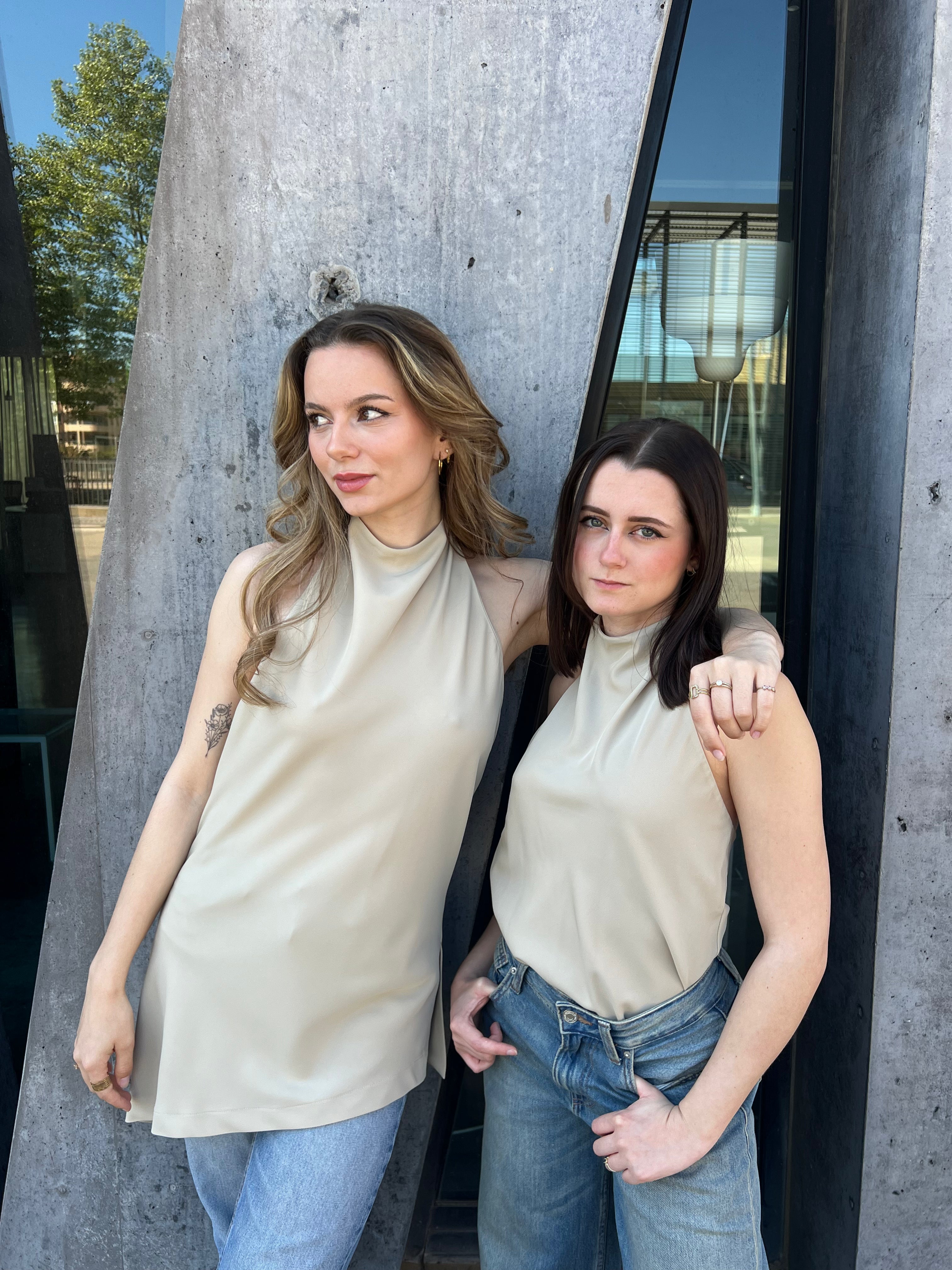 Deux modèles portant le haut asymétrique Lise vert d’eau de Nilai Fashion, face à un mur